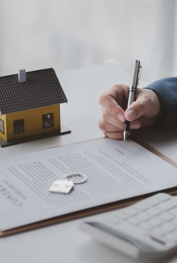 House and real estate agents, house salesmen with house models and house purchase contract documents