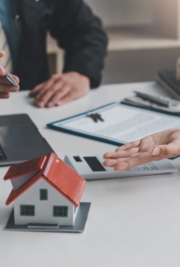 Real estate agents discuss the terms of the contract for the sale of the house at the office.