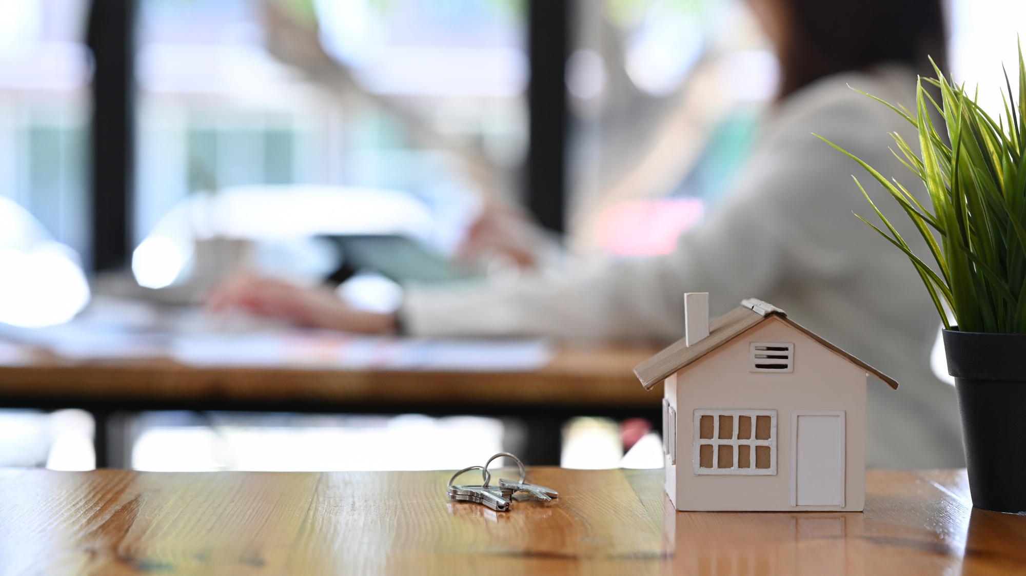 Small house model and house key on wooden table. Concept of real estate investment and insurance.