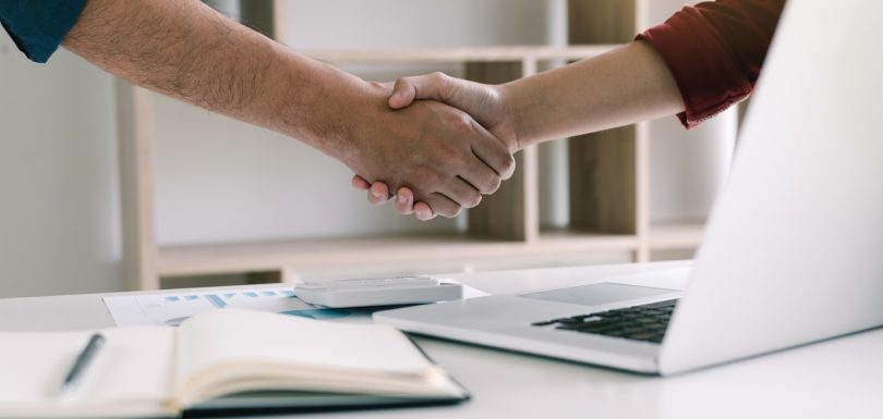 Co-worker startup shaking hands with colleagues in home office.