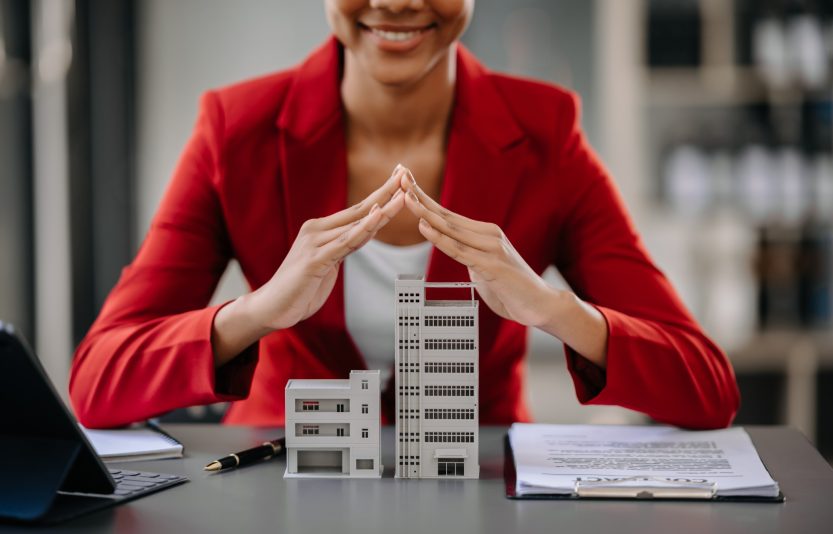 Female real estate agent is use hands to protect red roof for the concept of real estate investment