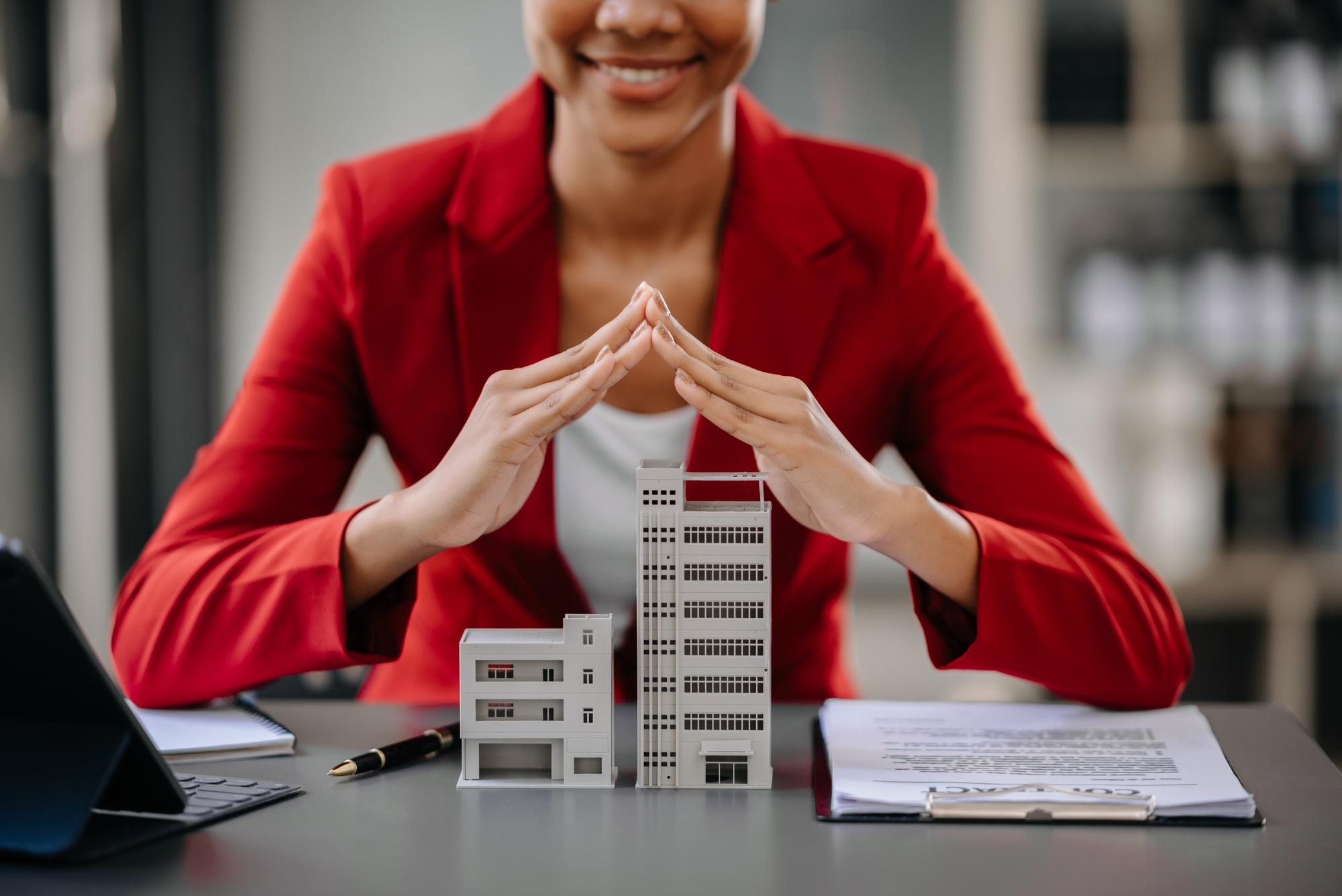 Female real estate agent is use hands to protect red roof for the concept of real estate investment